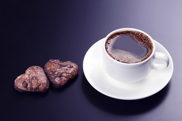 white cup of black coffee with biscuits on a dark background