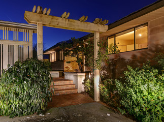 Sunset view of two story home with decorative pergola