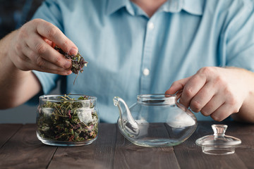 Fototapeta na wymiar Male hands Puts herbal tea in the kettle