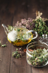 Dried herbs on wooden table and kettle wfor tea