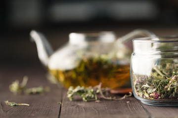 Dried herbs on wooden table and kettle wfor tea