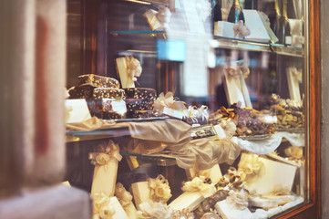 Rich variety of chocolates, candies and biscuits with a gift box in display window of italian...
