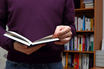 Mann im violetten Pullover blättert in einem Buch