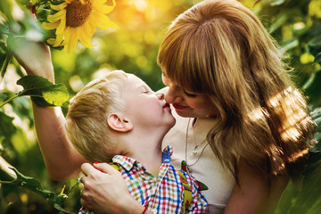 Young mum with small son among sunflowers