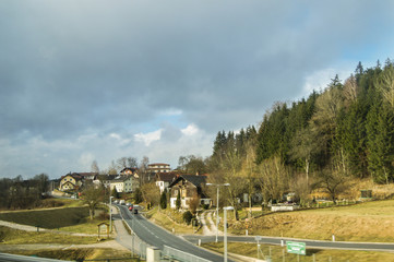 The road is along the village by the forest.