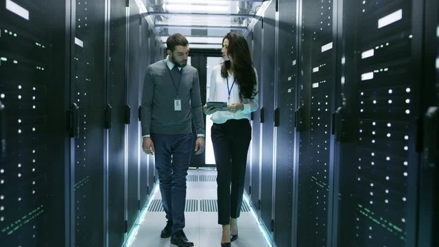 IT Specialist Showing Working Data Center with Rows of Rack Servers to His Female Colleague. Shot on RED EPIC-W 8K Helium Cinema Camera.