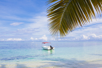 A motorboat moored near the tropical island in the turquoise waters of the Indian Ocean