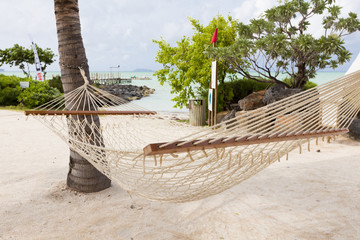 Empty hammock on tropical beach with palm  trees in the background