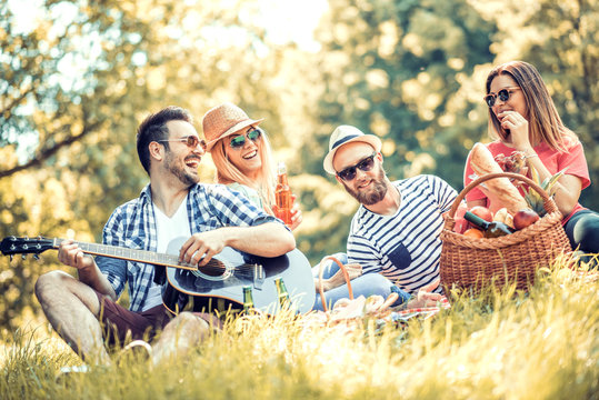 Happy Young Friends Having Picnic In The Park