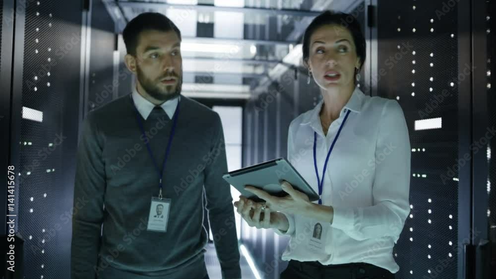 Poster two it engineers walking in data center/ server room, talking, running diagnostics with tablet compu