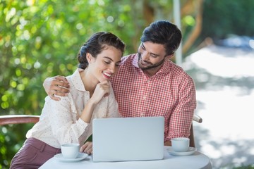 Couple smiling while using laptop