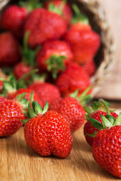 Fresh ripe strawberries in basket on a wooden background