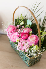 Fototapeta na wymiar Flower arrangement in basket with ranunculus and small pink and