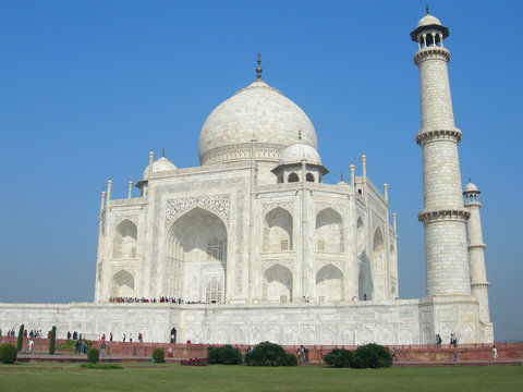 Side view of the Taj Mahal mausoleum in Agra, India, with the dome and the minaret towers and the lawn from the surrounding park