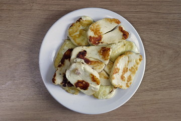 Grilled halloumi cheese on the plate. On the wooden table.