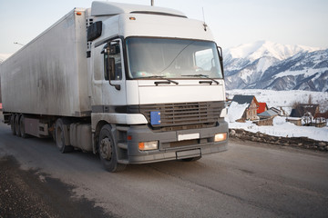 White refrigerated truck on winter road on background of the mountains