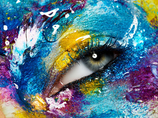 Fashion and beauty. Perfect female face. Colorful body art and artistic liquid makeup. Macro shot. Closeup of beautiful female eye with creative, colorful makeup
