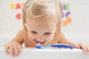 Smiling girl with toothbrush in bathroom