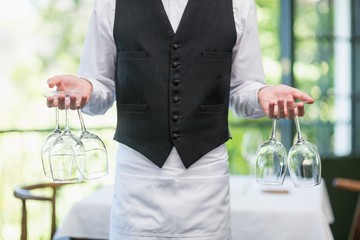 Male waiter holding wine glasses in the restaurant