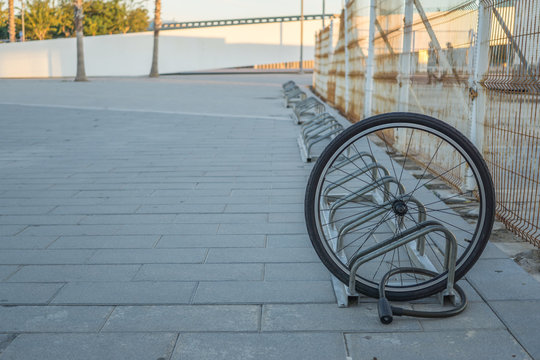 Fototapeta A damaged bike wheel is all that is left of a bicycle chained to a bike stand, a single bicycle wheel on the street due to stealing, Stolen bicycle, Chained bicycle wheel, front wheel locked