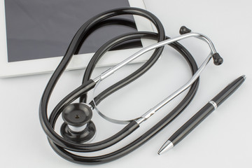 Tablet computer, pen and stethoscope on a white background