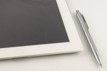 Tablet PC and a modern metal pen on a white background.