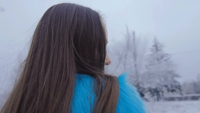 Beautiful cute girl with long hair posing in the winter forest.