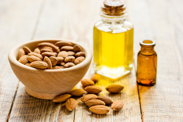 cosmetic and therapeutic almond oil on light wooden background