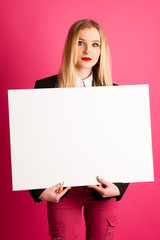 Young business woman holds blank banner isolated over pink background