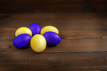 Yellow and purple Easter eggs on a wooden table. The concept of a holiday and a happy Easter
