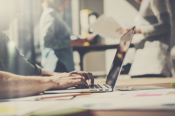 Man working at modern office.Coworker using laptop while sitting at the wooden table.Blurred...