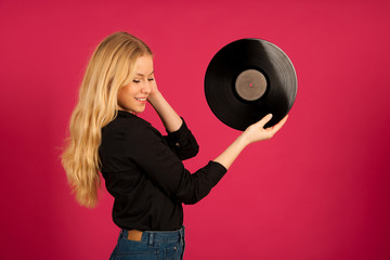 Beautiful young woman holding a vinyl in her hands as she listens to the music