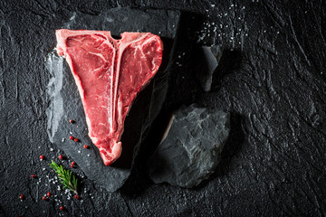 Fresh t-bone steak on black rock with salt and pepper