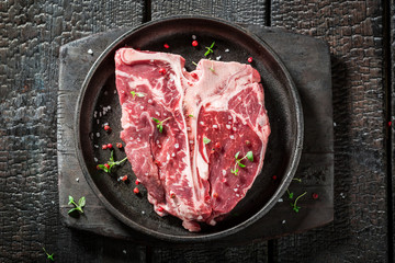 Raw t-bone steak with salt, pepper and rosemary