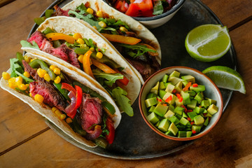 Tacos with pork, vegetables and salsa. Mexican kitchen. Wooden rustic background. Top view, flat, overhead. Copy space and text area.