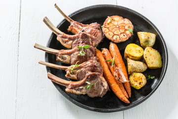 Tasty grilled ribs of lamb with vegetables on white table