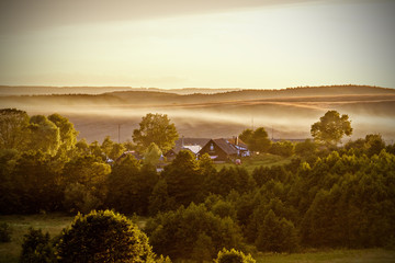 Fototapety  Rano z mgłą w domku we wsi o świcie do druku. Rezydencja dla rodziny i szczęścia