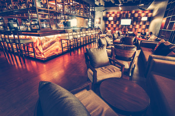 A modern restaurant cafe interior with chair, table, sofa, lighting and bar decoration wall with alcohol ssortment. Concept of relaxing outside and communication. Vintage toning, dark lights