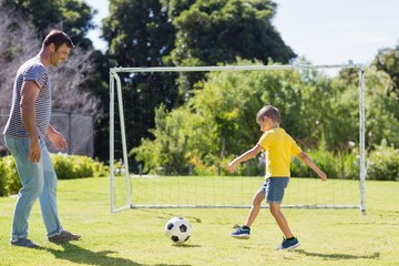 Father and son playing football in the park