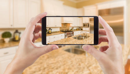 Female Hands Holding Smart Phone Displaying Photo of Kitchen Behind. © Andy Dean