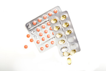 Red pills and capsules of cod-liver oil in blisters