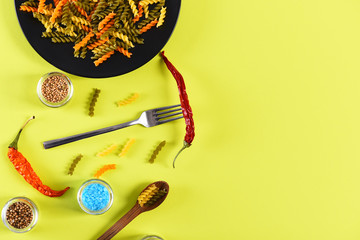 Colorful dried fusilli pasta with salt crystals on black plate