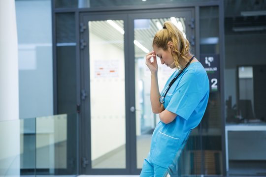 Upset female doctor standing in corridor
