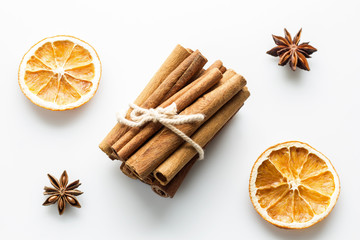 Cinnamon sticks with star orange slices on white background.