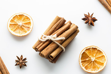 Cinnamon sticks with star orange slices on white background.