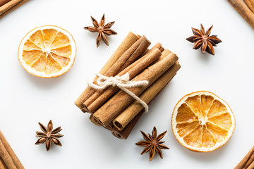 Fototapeta na wymiar Cinnamon sticks with star orange slices on white background.