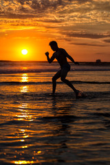 Fototapeta na wymiar Silhouette of young male capoeira dancer, yoga and martial art specialist at beach in Mexico during spectacular sunset