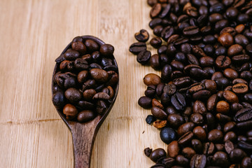 Coffee beans in wood spoon over the chop board
