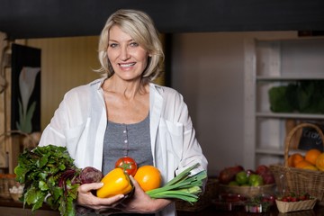 Portrait female costumer holding fresh vegetables 