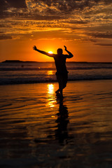 Silhouette of young male capoeira dancer, yoga and martial art specialist at beach in Mexico during spectacular sunset